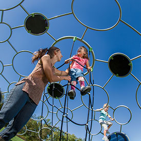 Parent with child playing on a climbing dome